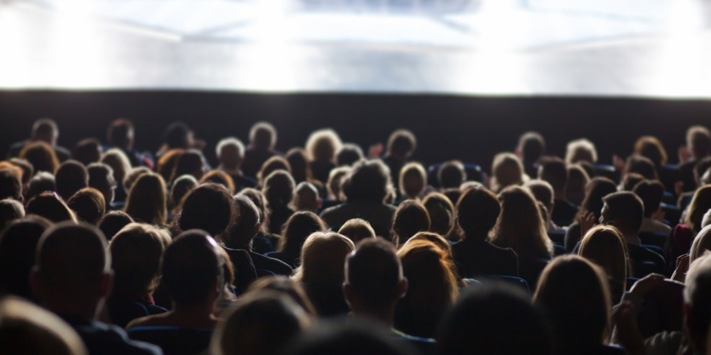 Rearview of rows of people watching a performance in a theater